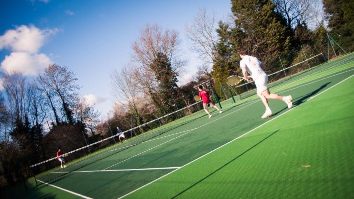 Students playing tennis in the College tennis courts next to Leckhampton