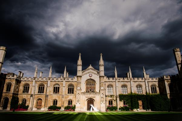 Bride & groom, and a stormy sky over the Chapel | Photo credit : Alex Beckett Photography 